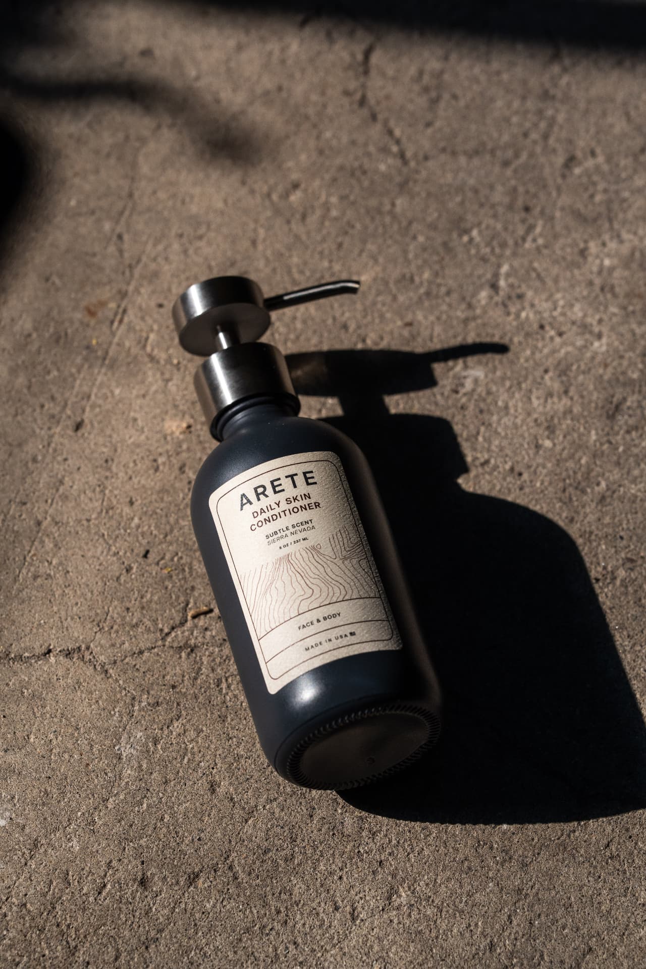 ARETE bottle in hard natural sunlight on concrete